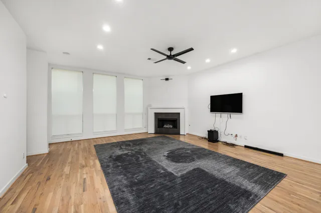 a view of a livingroom with a fireplace a ceiling fan and wooden floor