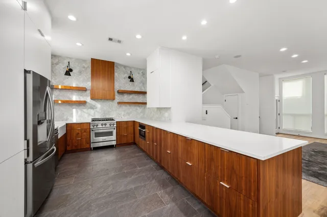 a large kitchen with stainless steel appliances a large counter top a stove a refrigerator and a sink