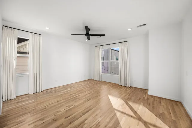 a view of empty room with wooden floor and window