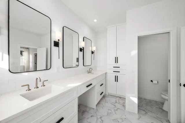 a bathroom with a double vanity sink mirror and toilet