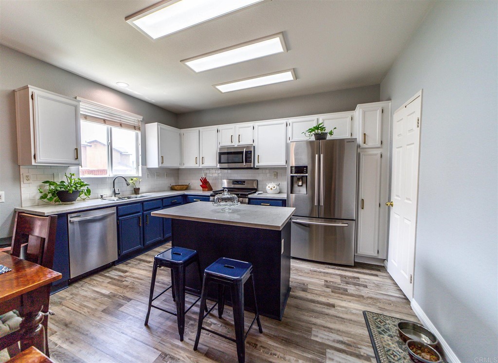 31047 Rose Circle Murrieta, CA 92563 - Photo 4 of 20 a kitchen with a refrigerator a stove a sink dishwasher with a dining table and chair with wooden floor