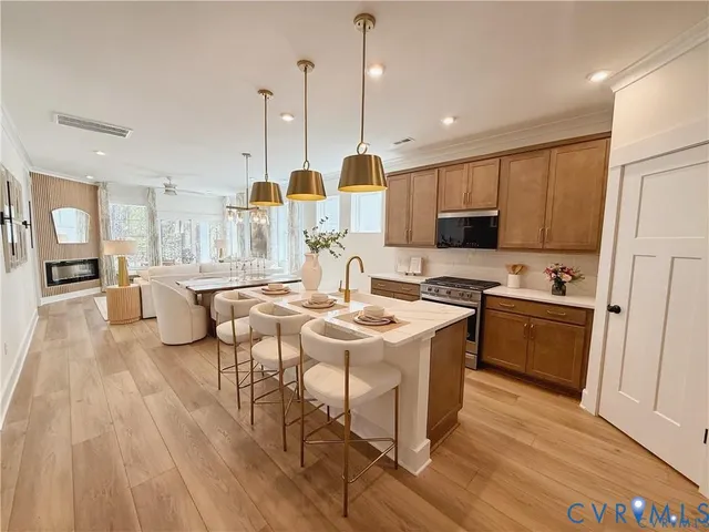 a kitchen with stainless steel appliances granite countertop a sink a stove and a wooden floors