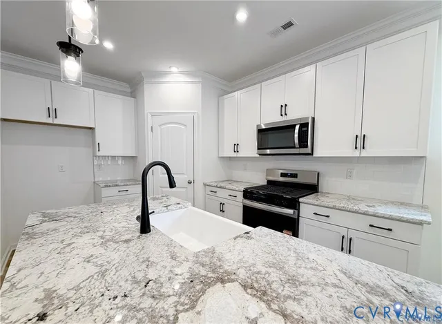 a kitchen with granite countertop a stove a sink and a refrigerator