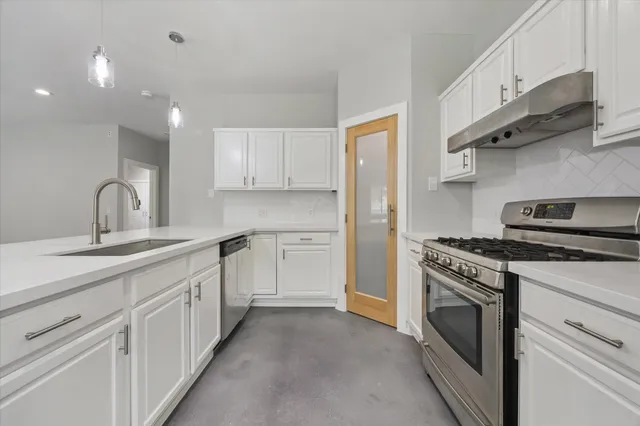 a kitchen with stainless steel appliances granite countertop white cabinets and a sink