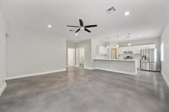 an empty room with windows and ceiling fan