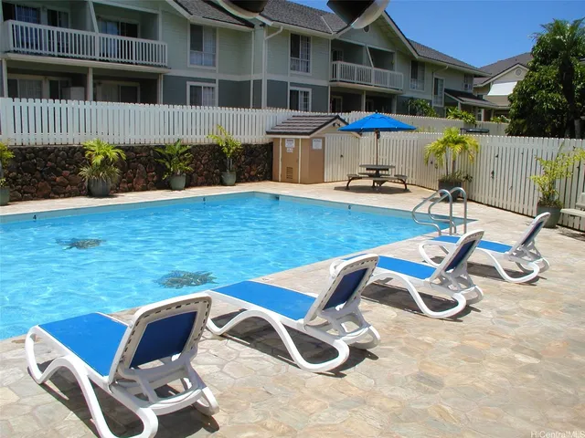 a view of a swimming pool with chairs and plants