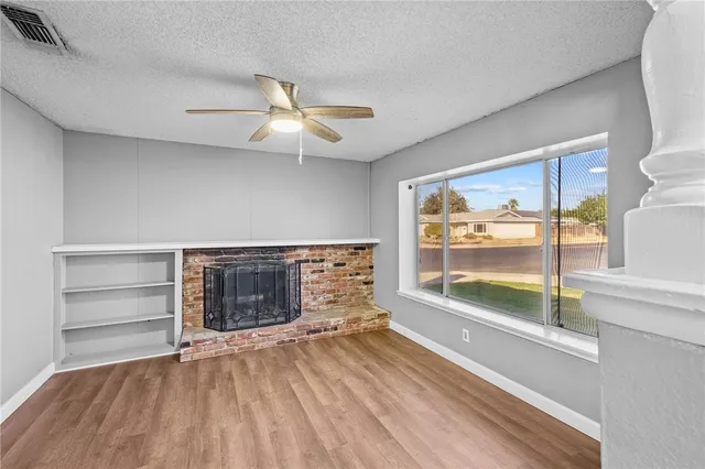 a view of a livingroom with wooden floor a ceiling fan and window