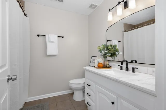 a bathroom with a granite countertop sink a toilet and mirror