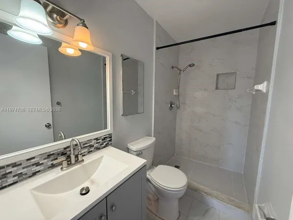 a bathroom with a sink toilet a mirror and shower