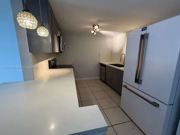 a view of a refrigerator in kitchen and an empty room