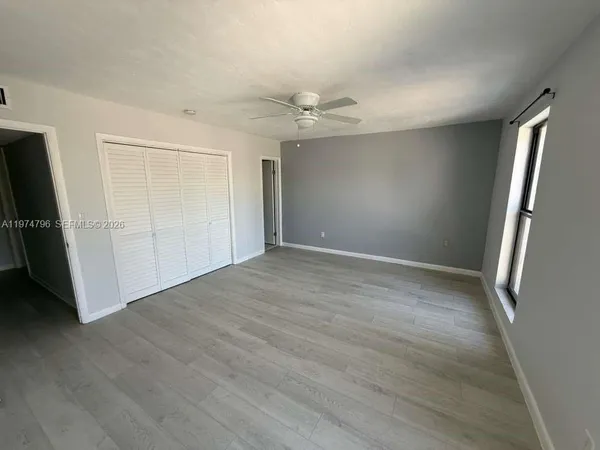 an empty room with wooden floor and a ceiling fan