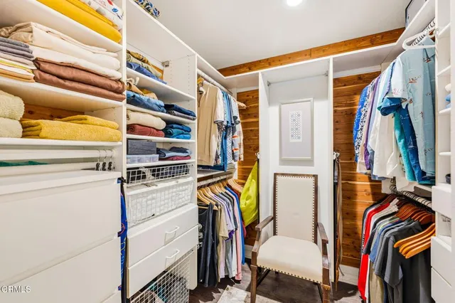 a view of walk in closet with clothes and shoes
