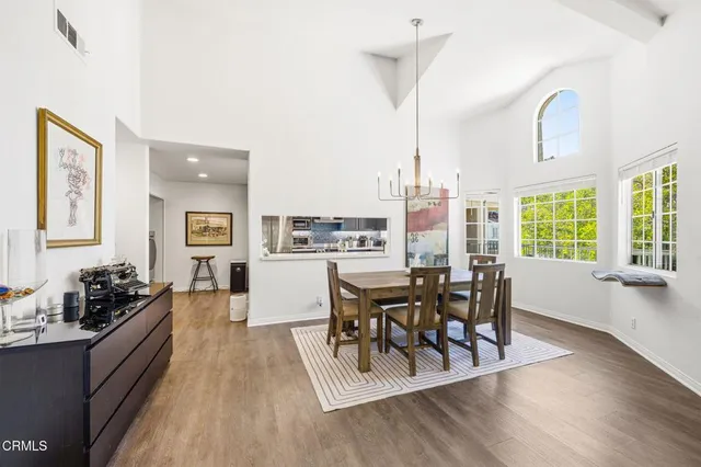 a dining room with wooden floor a chandelier a glass table and chairs
