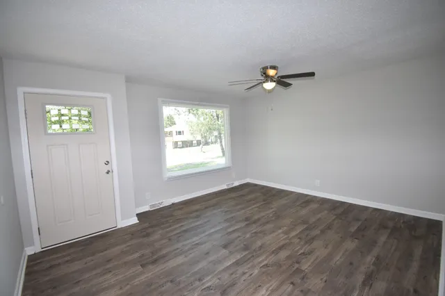 an empty room with wooden floor and windows