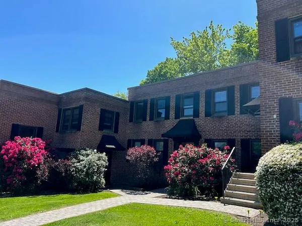 a front view of house and yard with beautiful flowers and green space