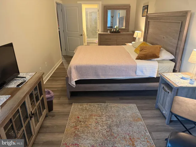 a bedroom with a bed next to a window with wooden floor