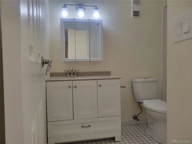 a bathroom with a granite countertop toilet and sink