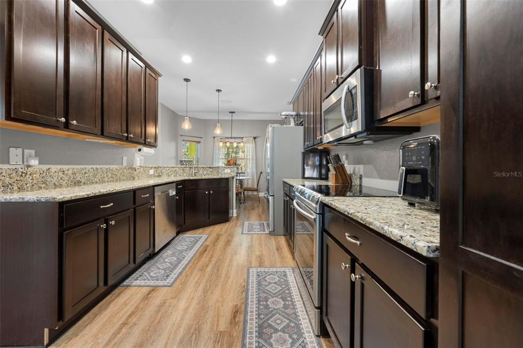 8104 Nightingale Road Weeki Wachee, FL 34613 - Photo 23 of 45 a large kitchen with stainless steel appliances granite countertop plenty wooden cabinets counter space a sink and wooden floor