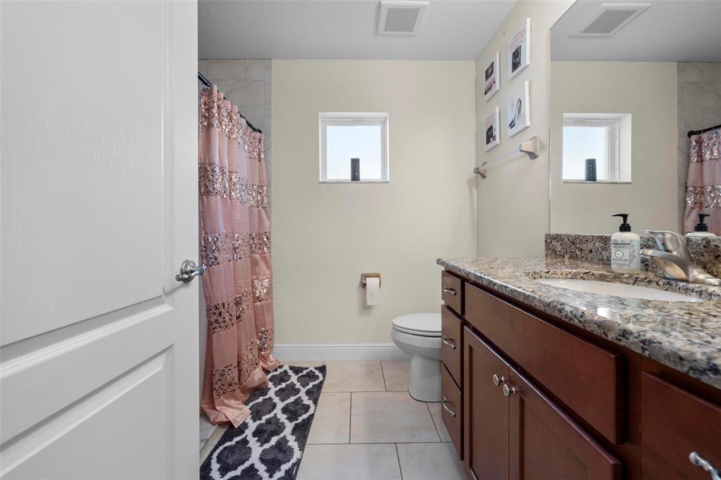 8104 Nightingale Road Weeki Wachee, FL 34613 - Photo 38 of 45 a bathroom with a granite countertop sink a toilet and a shower