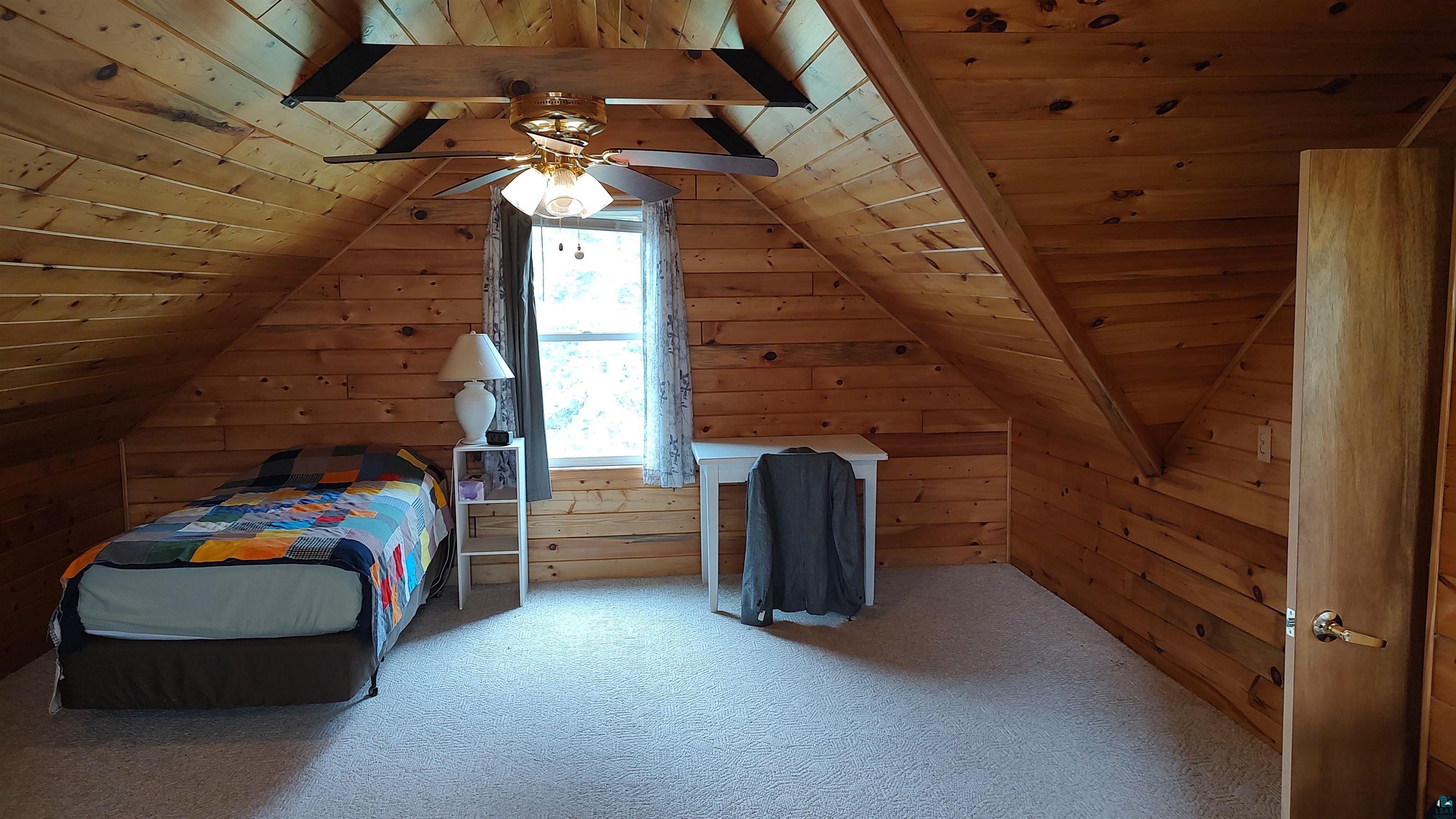2585 Hautala Road Iron River, WI 54847 - Photo 12 of 28 Attic space featuring wood-paneled walls and ceiling, a ceiling fan, and carpeted flooring