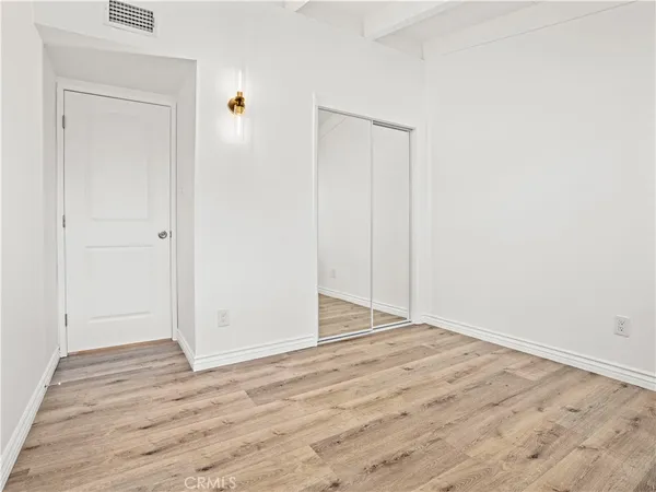 a view of an empty room with wooden floor and closet