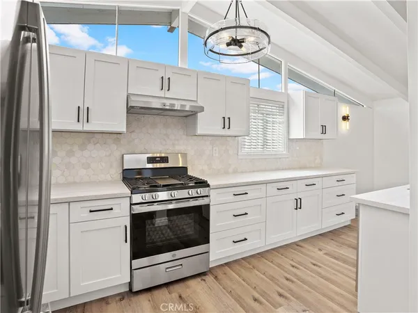 a kitchen with cabinets stainless steel appliances and wooden floor