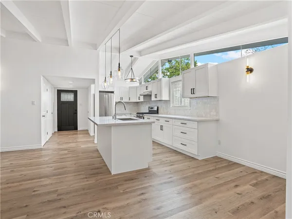 a kitchen with white cabinets and wooden floor