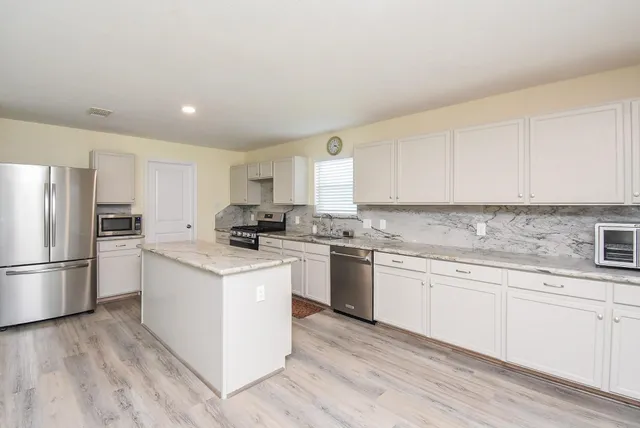 a kitchen with granite countertop white cabinets and white appliances