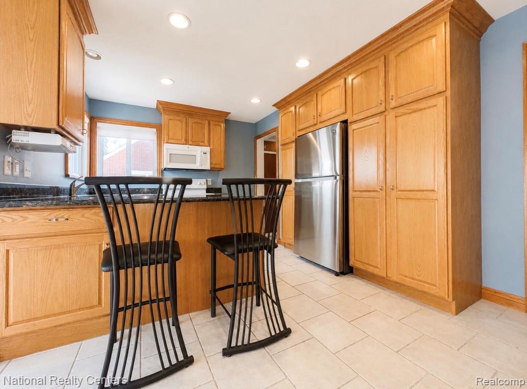 7285 Helen Street Center Line, MI 48015 - Photo 11 of 32 Kitchen featuring recessed lighting, a stainless steel refrigerator, light wood-finish cabinetry, a black countertop, and light-toned tile flooring