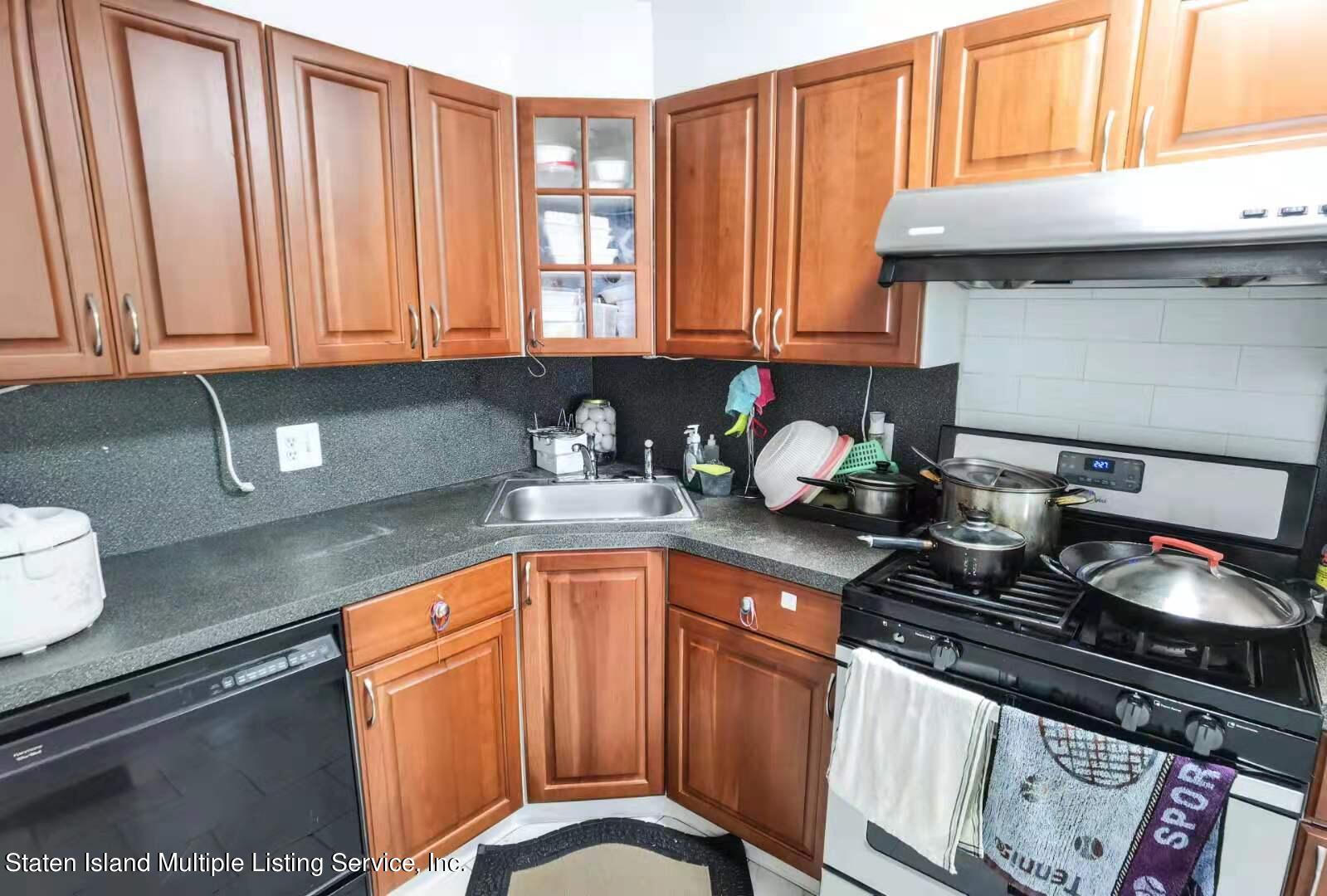 44 Chesebrough Street Staten Island, NY 10312 - Photo 10 of 24 a kitchen with granite countertop a stove a sink dishwasher and cabinets with wooden floor