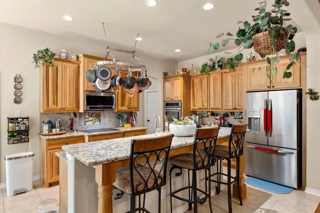 a kitchen with stainless steel appliances granite countertop a table chairs and a refrigerator