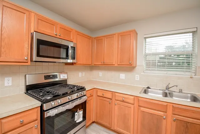 a kitchen with granite countertop cabinets stainless steel appliances a sink and a window