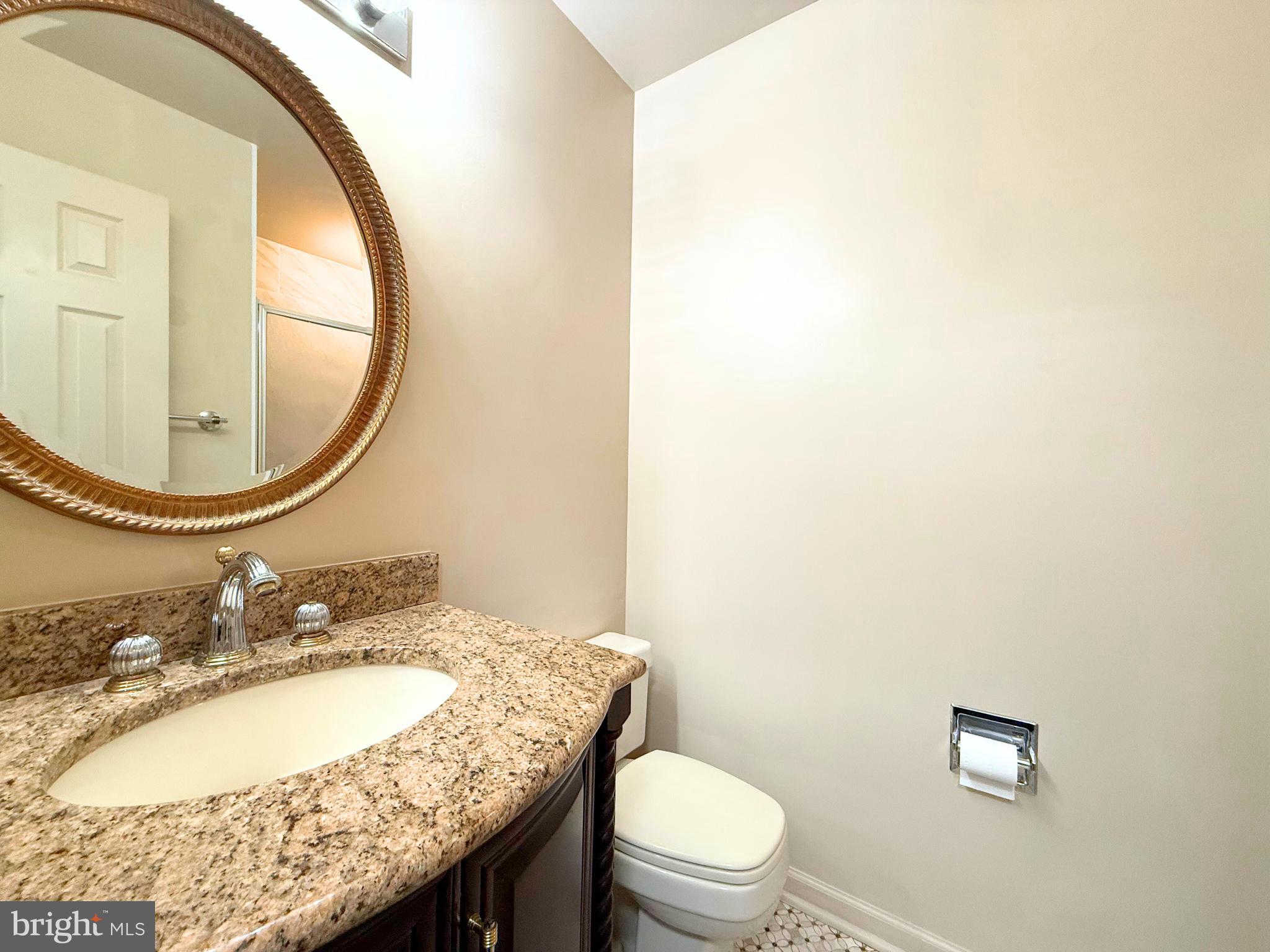 10706 Kings Riding Way, Unit 20118 Rockville, MD 20852 - Photo 18 of 24 a bathroom with a granite countertop toilet a sink and a mirror