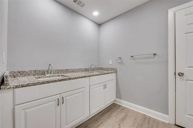 a bathroom with a granite countertop sink and white cabinets
