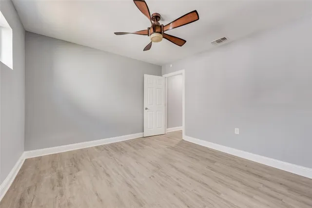 an empty room with wooden floor and a ceiling fan