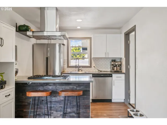 a kitchen with kitchen island granite countertop a sink cabinets and stainless steel appliances