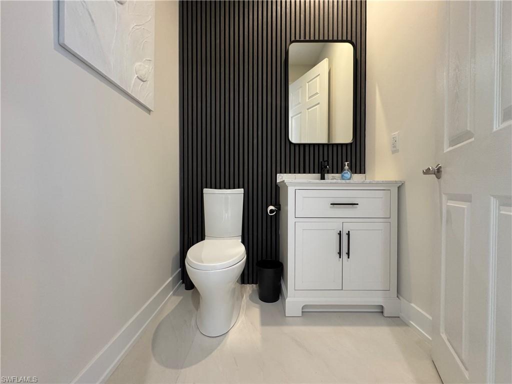 12667 Biscayne Court Naples, FL 34105 - Photo 14 of 41 a bathroom with a toilet sink vanity and mirror