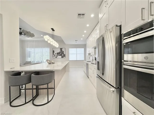 a kitchen with stainless steel appliances kitchen island granite countertop a table chairs in it and wooden floors