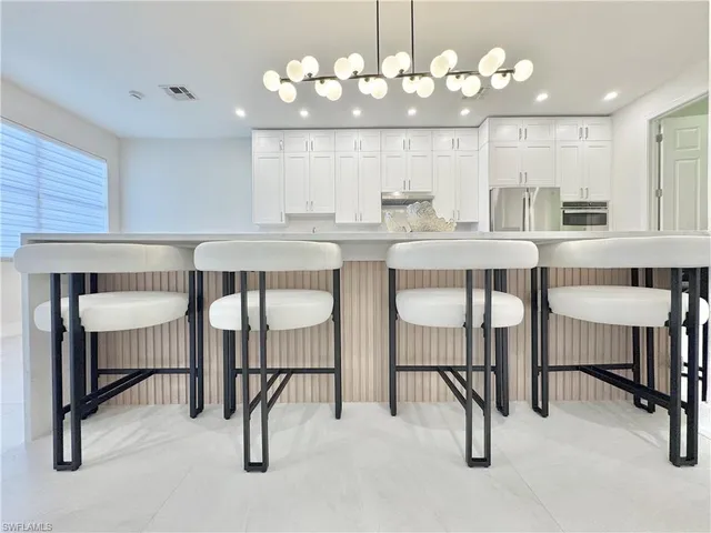 a kitchen with stainless steel appliances granite countertop a table chairs sink and cabinets