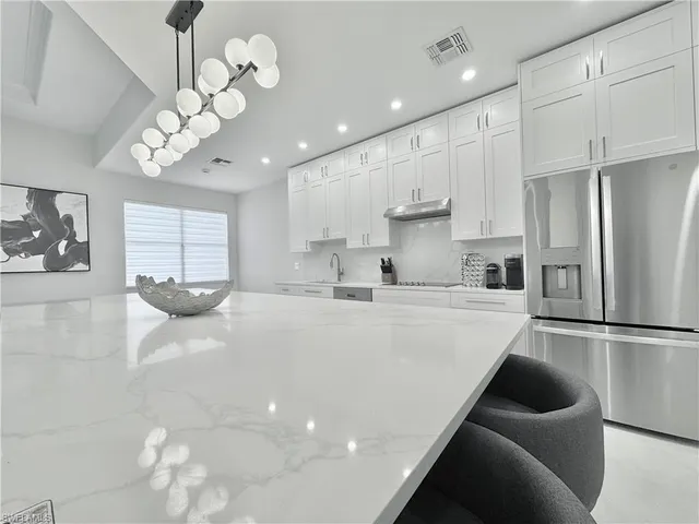 a large white kitchen with lots of counter space wooden floor cabinets and a refrigerator