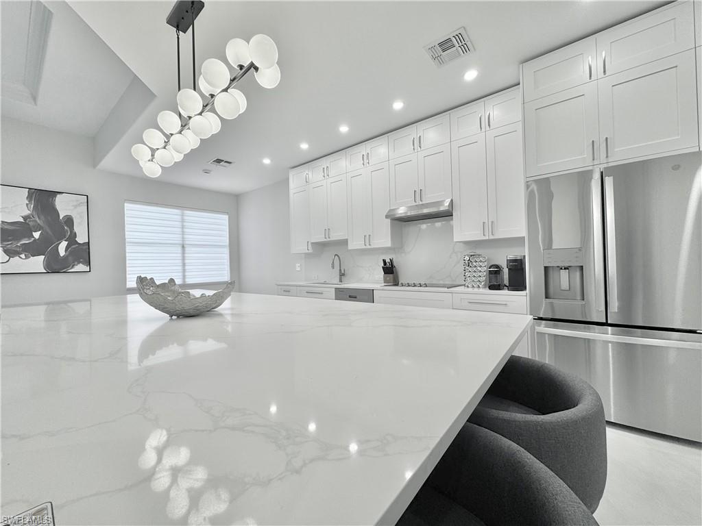 12667 Biscayne Court Naples, FL 34105 - Photo 23 of 41 a large white kitchen with lots of counter space wooden floor cabinets and a refrigerator