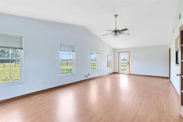 a view of empty room with wooden floor and fan