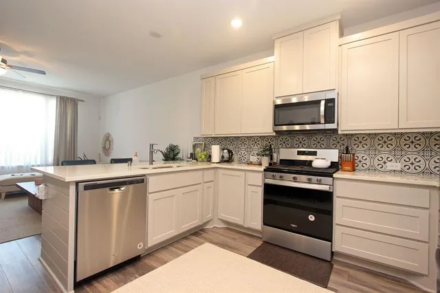 a kitchen with stainless steel appliances granite countertop a stove a sink and a microwave