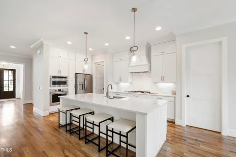 a kitchen with kitchen island a stove a table and chairs in it