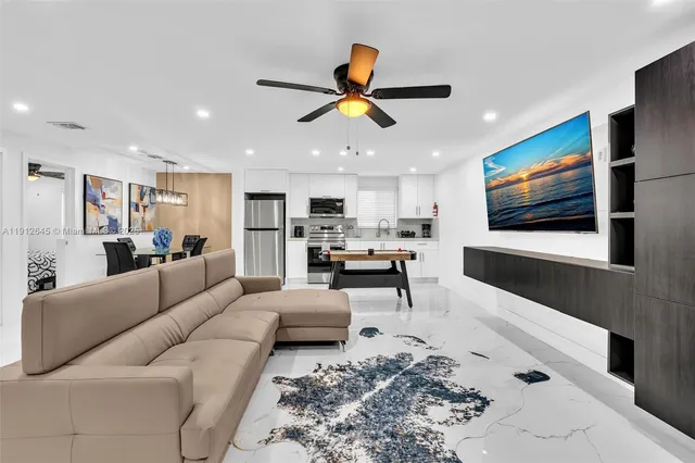 a living room with furniture kitchen view and a window