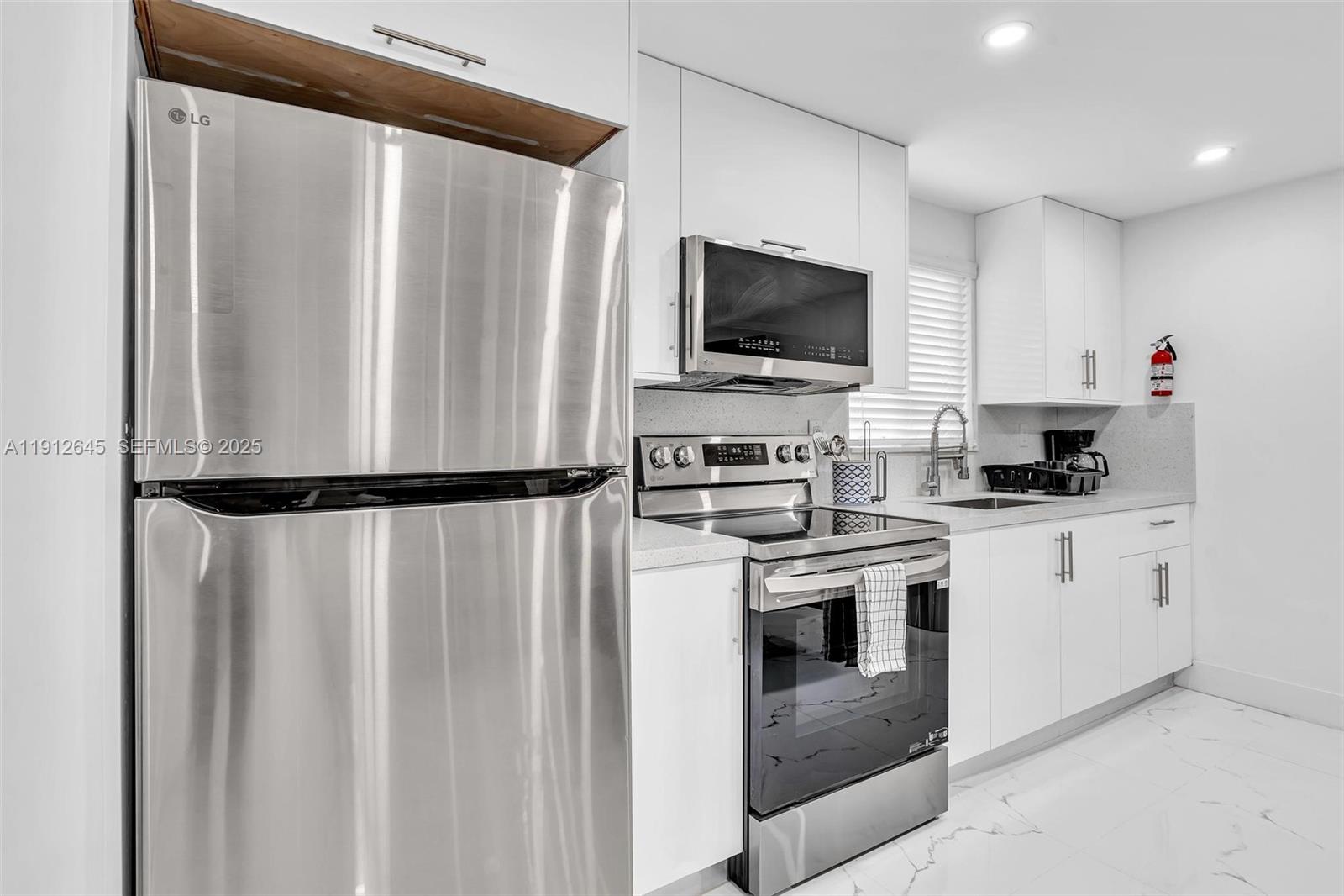 923 Northwest 110th Street, Unit A Miami, FL 33168 - Photo 13 of 21 a kitchen with stainless steel appliances white cabinets and a refrigerator