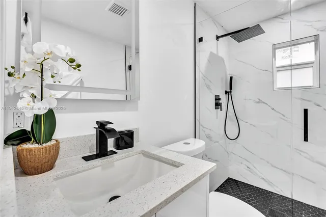 a bathroom with a sink a toilet and shower