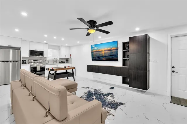 a kitchen with stainless steel appliances kitchen island granite countertop a refrigerator a stove top oven a sink dishwasher and white cabinets with wooden floor