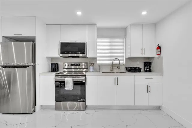 a kitchen with white cabinets and stainless steel appliances
