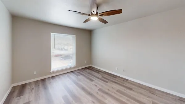 an empty room with wooden floor fireplace and windows